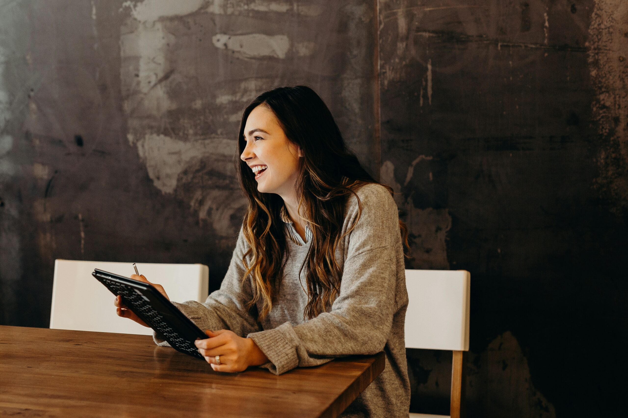 Una mujer sonriente sosteniendo una tablet, representando el uso de tecnología para el éxito académico.