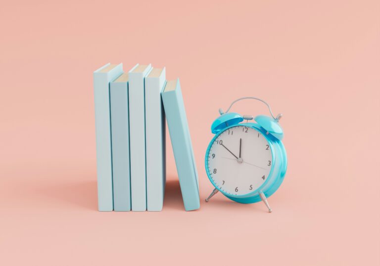Reloj despertador antiguo sobre una pila de libros simbolizando la organización del tiempo de estudio.