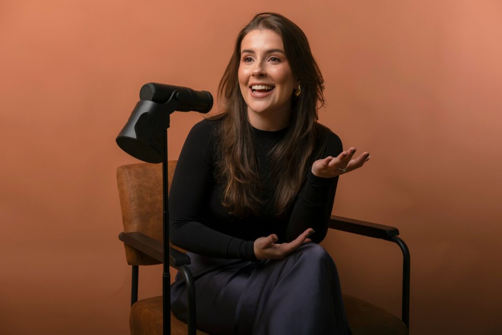 Una mujer que es estudiante sosteniendo un micrófono y practicando su discurso en un entorno de práctica.