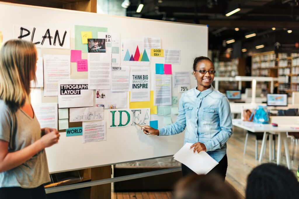 Dos intraemprendedoras presentando un plan de negocios para validar la arquitectura empresarial ante stakeholders.
