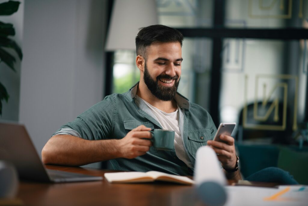 Un hombre leyendo un libro en una aplicación de audiolibros en su celular para adquirir conocimiento.